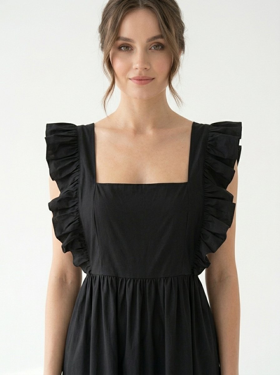 Mannequin portant la robe mi-longue noire 'Shadow' avec encolure carrée, bretelles à volants et jupe froncée, de la marque Divine Dress.