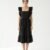 Mannequin portant la robe mi-longue noire 'Shadow' avec encolure carrée, bretelles à volants et jupe froncée, de la marque Divine Dress.