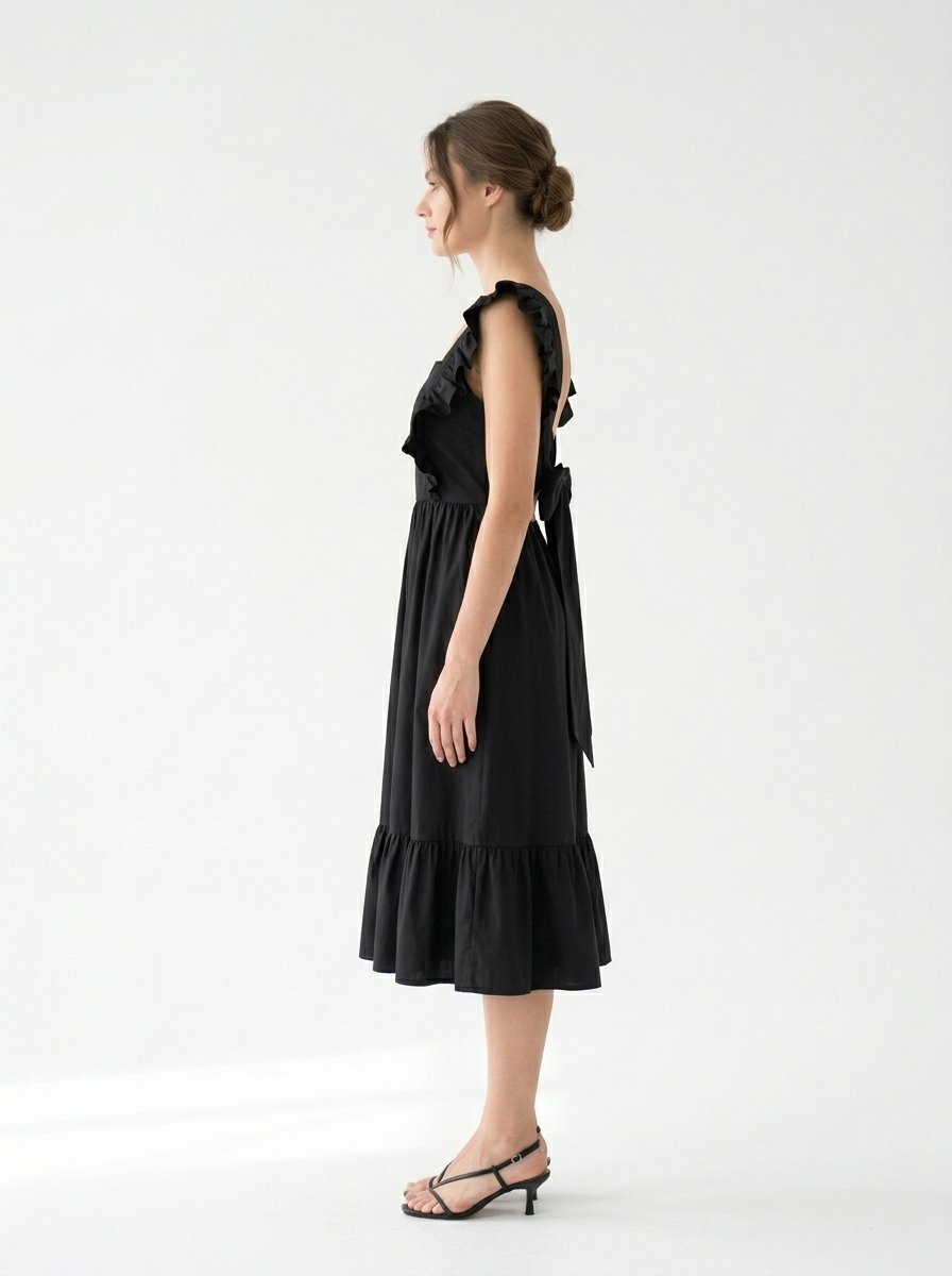 Mannequin portant la robe mi-longue noire 'Shadow' avec encolure carrée, bretelles à volants et jupe froncée, de la marque Divine Dress.