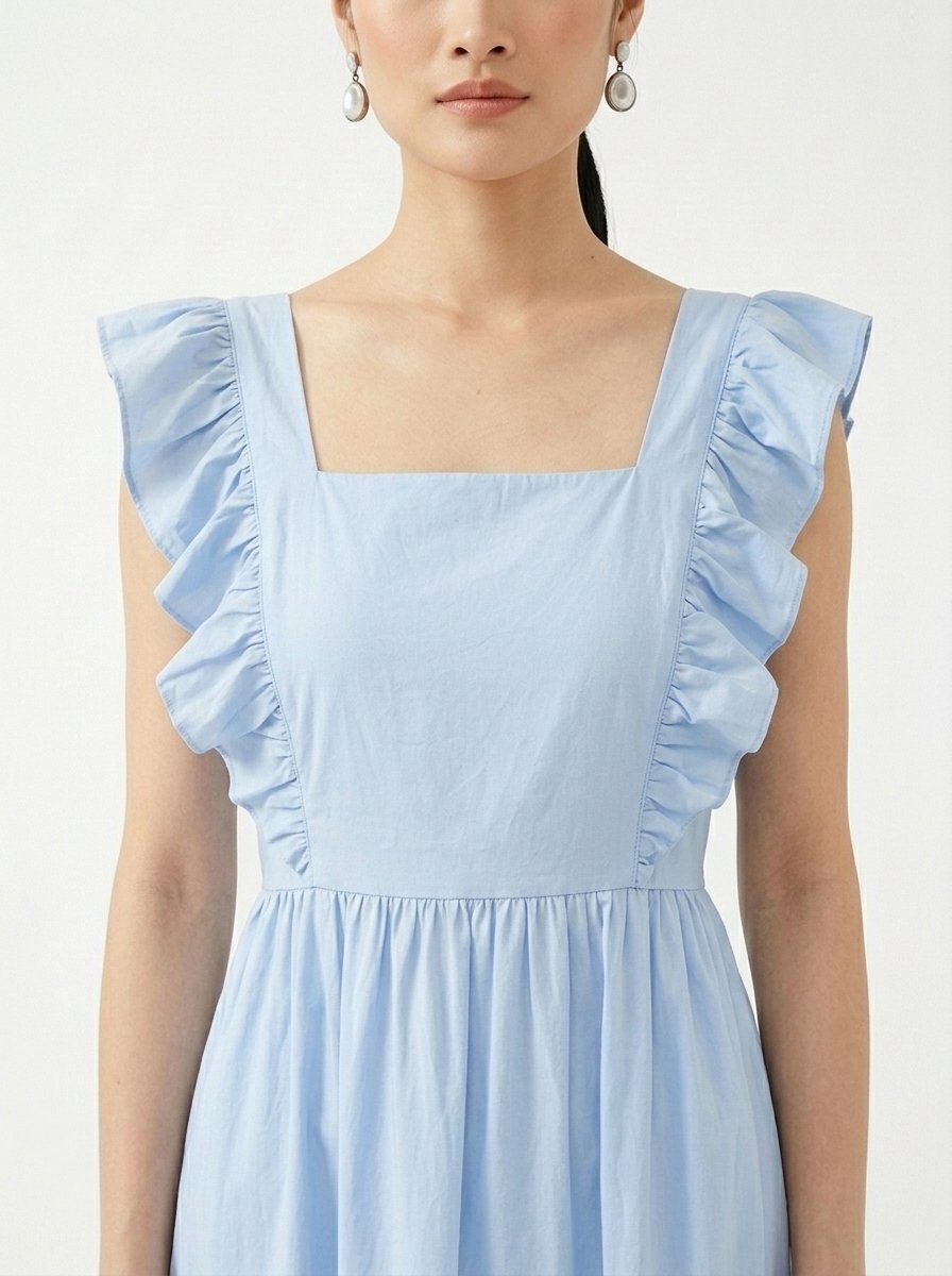 Mannequin portant la robe mi-longue bleu clair 'Shadow' avec encolure carrée, bretelles à volants et jupe froncée, de la marque Divine Dress.