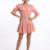 Mannequin portant la robe courte rose 'Pink Petal' avec col à volants, manches froncées à nouer et double fine ceinture, de la marque Divine Dress.