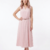 Mannequin portant la robe midi rose clair 'Summer Serenity', sans manches avec un col en V discret et une fine ceinture, de la marque Divine Dress.