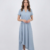 Mannequin portant la robe asymétrique bleu 'Fluid Grace' avec manches courtes, col en V et jupe fluide drapée, de la marque Divine Dress.