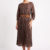 Mannequin portant la robe midi marron 'Velvet Touch' avec jupe plissée, manches 3/4 et large ceinture décorative, signée Divine Dress.