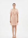 Mannequin portant la robe courte couleur pêche 'Peach' avec large col à volants, lien à nouer et manches courtes bouffantes, de la marque Divine Dress.