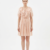 Mannequin portant la robe courte couleur pêche 'Peach' avec large col à volants, lien à nouer et manches courtes bouffantes, de la marque Divine Dress.