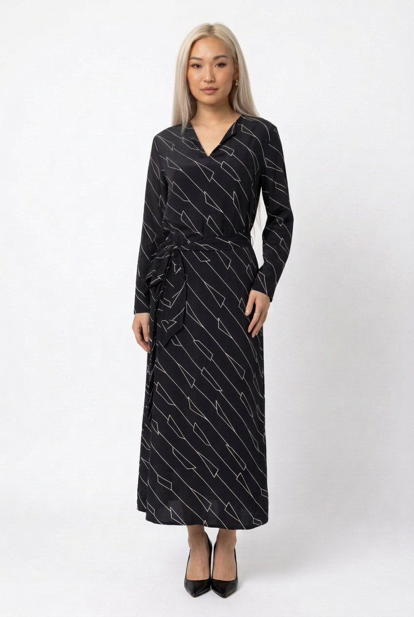 Mannequin portant la robe longue noir à motif géométrique 'Geometric Grace', avec col en V, manches longues et ceinture à nouer, de la marque Divine Dress.