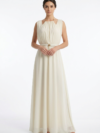 Mannequin portant la robe longue fluide crème 'Soft Lilac' avec encolure froncée, détails dorés et fine ceinture, de la marque Divine Dress.