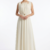 Mannequin portant la robe longue fluide crème 'Soft Lilac' avec encolure froncée, détails dorés et fine ceinture, de la marque Divine Dress.