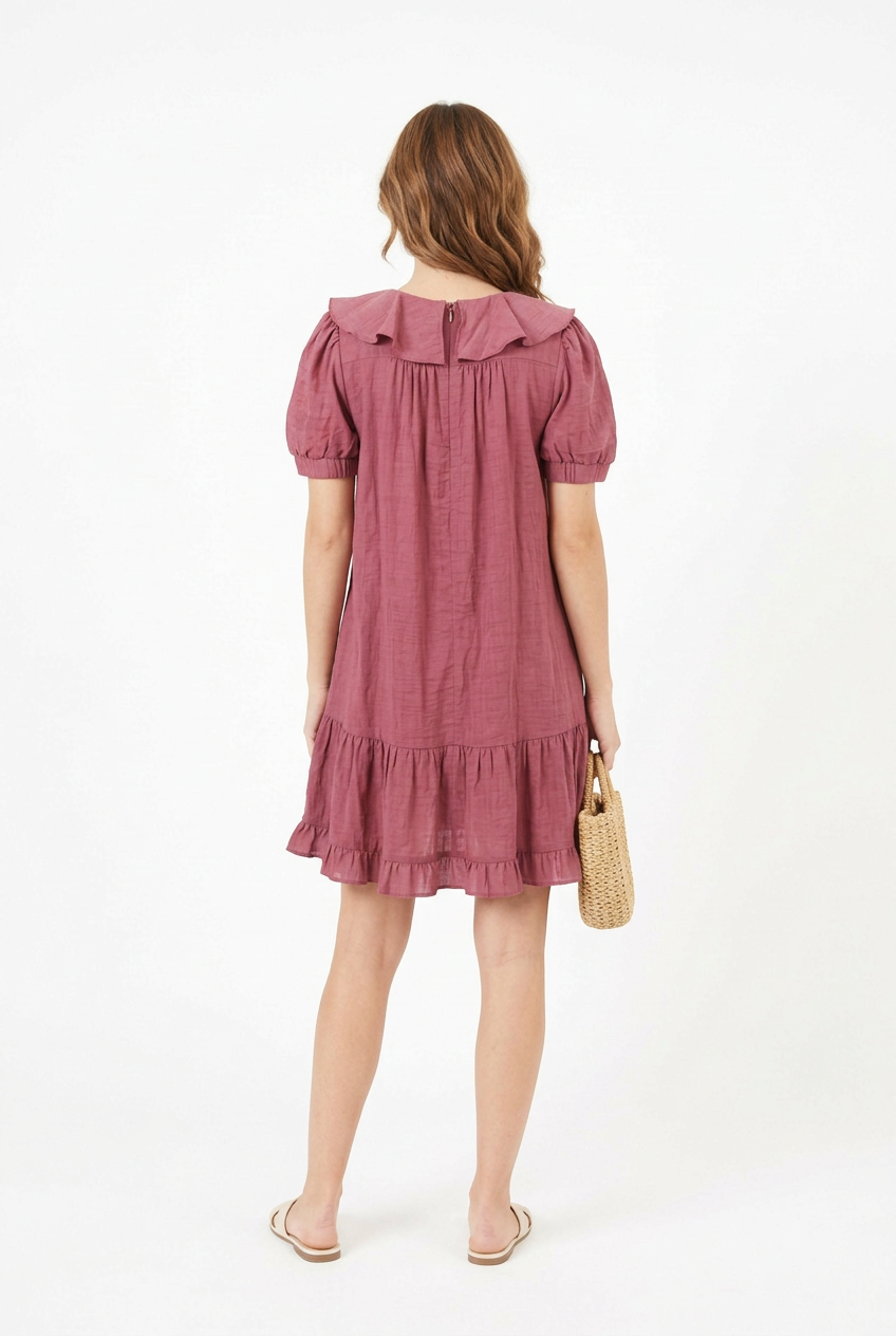 Mannequin portant la robe courte vieux rose 'Cascading' avec col à volants, manches courtes bouffantes et jupe asymétrique, de la marque Divine Dress.