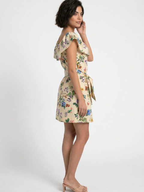 Mannequin portant la robe courte beige clair à imprimé floral 'Bow Elegance', avec large volant à l'encolure et ceinture nouée, de la marque Divine Dress