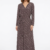 Mannequin portant la robe longue marron à motif géométrique 'Geometric Grace', avec col en V, manches longues et ceinture à nouer, de la marque Divine Dress.