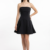 Mannequin portant la petite robe noire bustier 'Elegant Muse' avec jupe évasée, de la marque Divine Dress