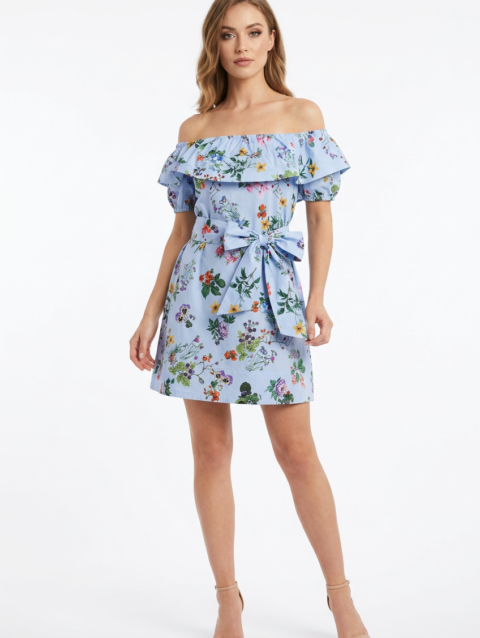 Mannequin portant la robe courte bleu clair à imprimé floral 'Bow Elegance', avec encolure Bardot à volants et grande ceinture nouée, de la marque Divine Dress