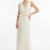 Mannequin portant la robe longue fluide blanc cassé 'Athena' avec décolleté en V, taille froncée à cordon et détails volantés, de la marque Divine Dress.