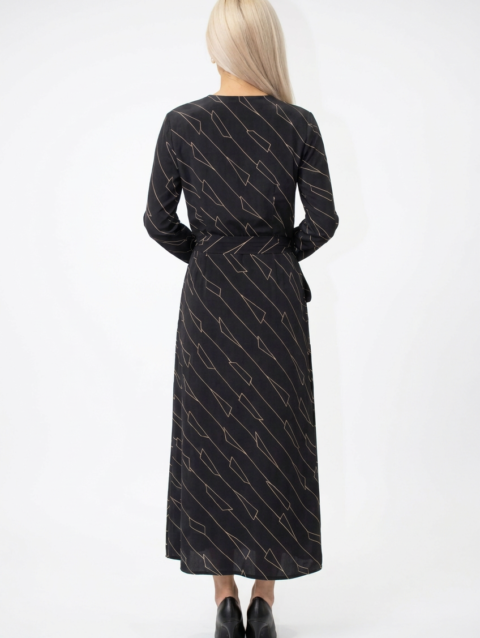 Mannequin portant la robe longue noir à motif géométrique 'Geometric Grace', avec col en V, manches longues et ceinture à nouer, de la marque Divine Dress.