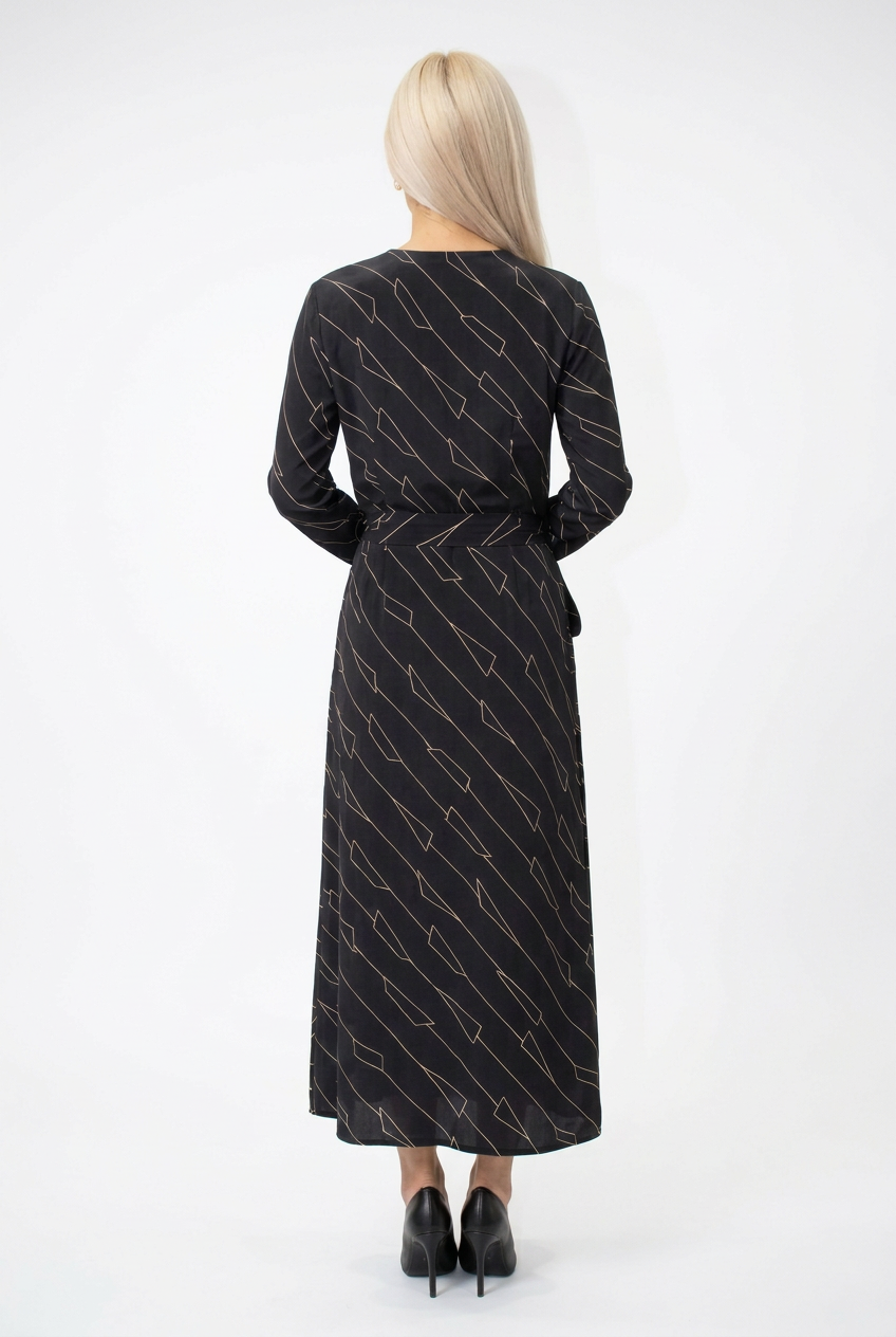 Mannequin portant la robe longue noir à motif géométrique 'Geometric Grace', avec col en V, manches longues et ceinture à nouer, de la marque Divine Dress.