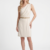 Mannequin portant la robe courte asymétrique crème 'Asymmetric' avec épaule drapée et fine ceinture dorée, de la marque Divine Dress.