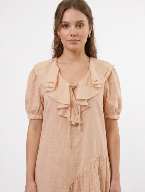 Mannequin portant la robe courte beige 'Cascading' avec col à volants, manches courtes bouffantes et jupe asymétrique, de la marque Divine Dress.