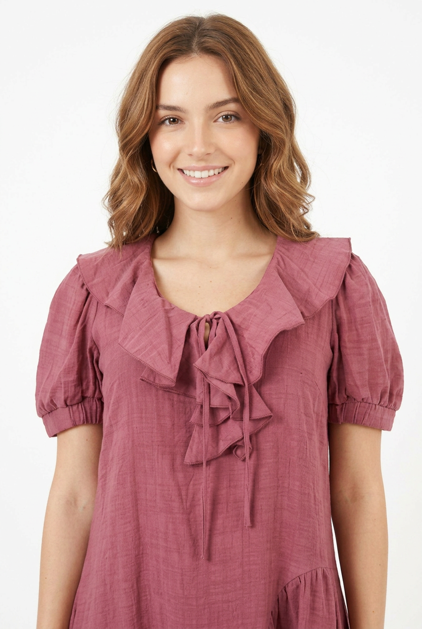 Mannequin portant la robe courte vieux rose 'Cascading' avec col à volants, manches courtes bouffantes et jupe asymétrique, de la marque Divine Dress.