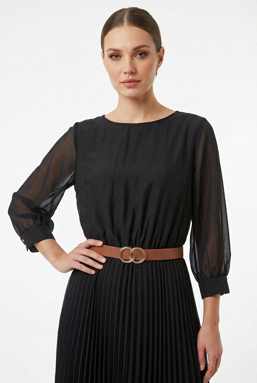 Mannequin portant la robe midi noir 'Velvet Touch' avec jupe plissée, manches 3/4 et large ceinture décorative, signée Divine Dress.